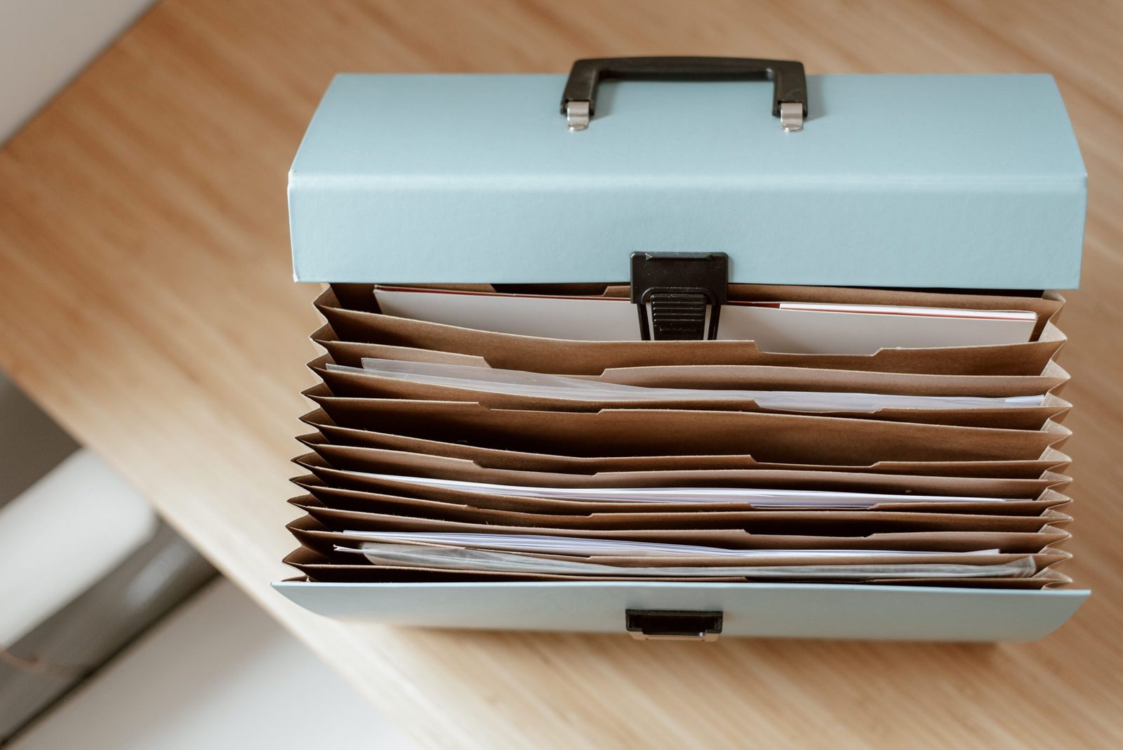An expanding file organiser full of papers on a wooden table