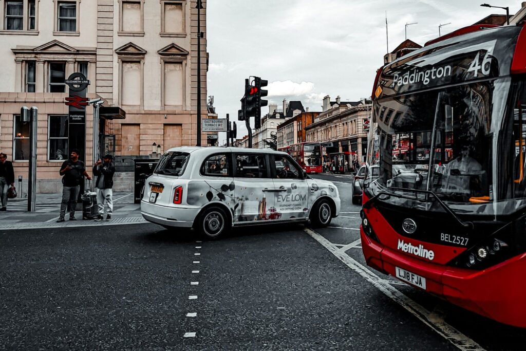 Red bus and white taxi at a London road junction