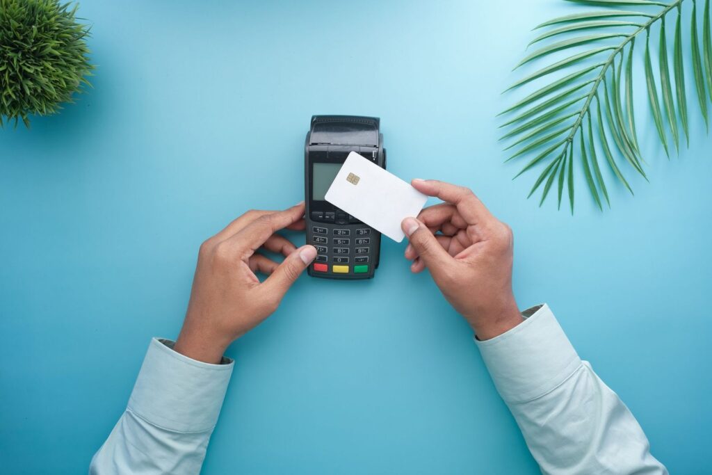 Hands holding a card next to a payment terminal