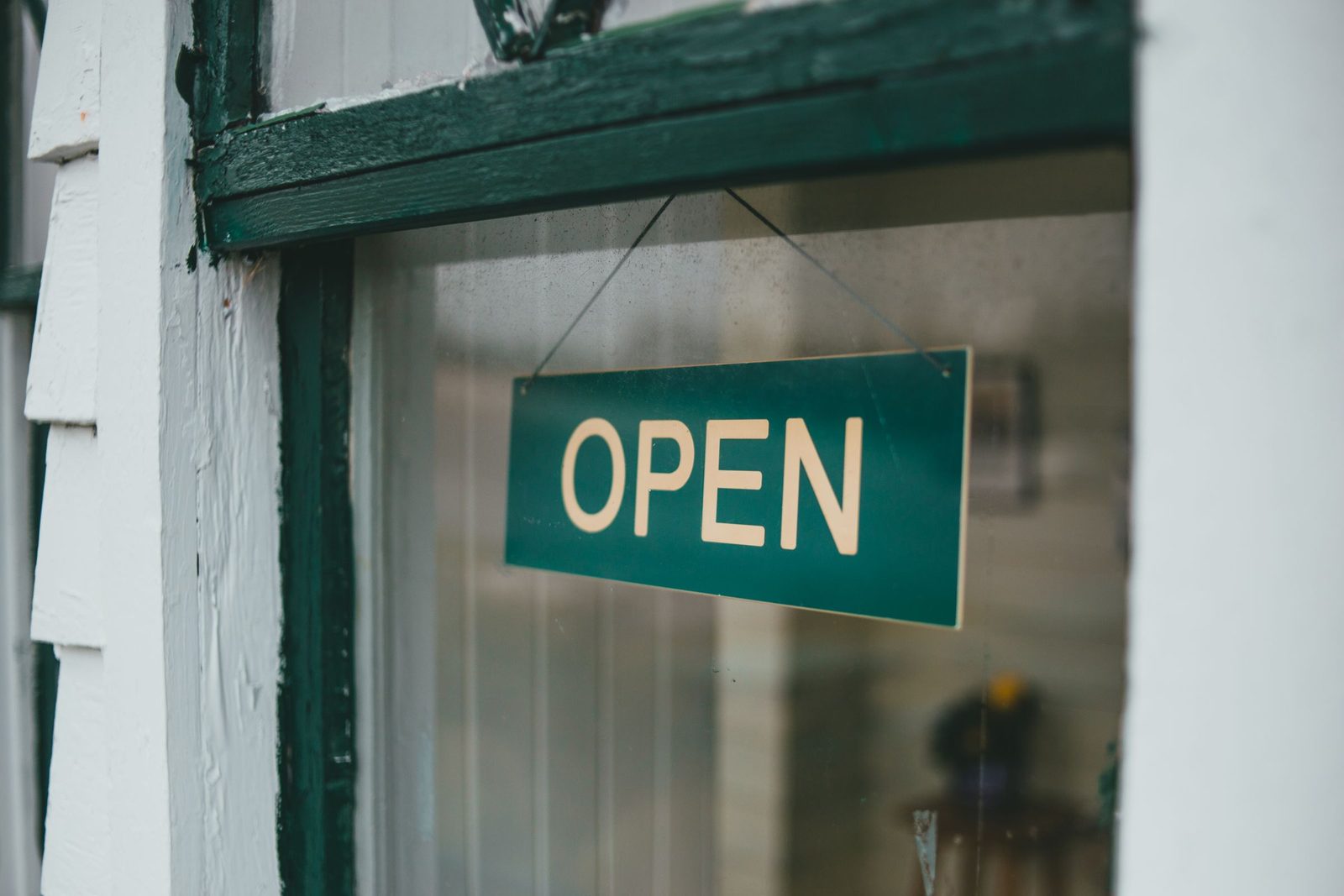 A green Open sign hanging in a shop window