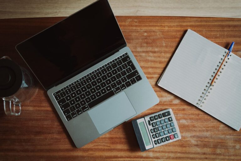 Laptop calculator and notebook on a wooden desk