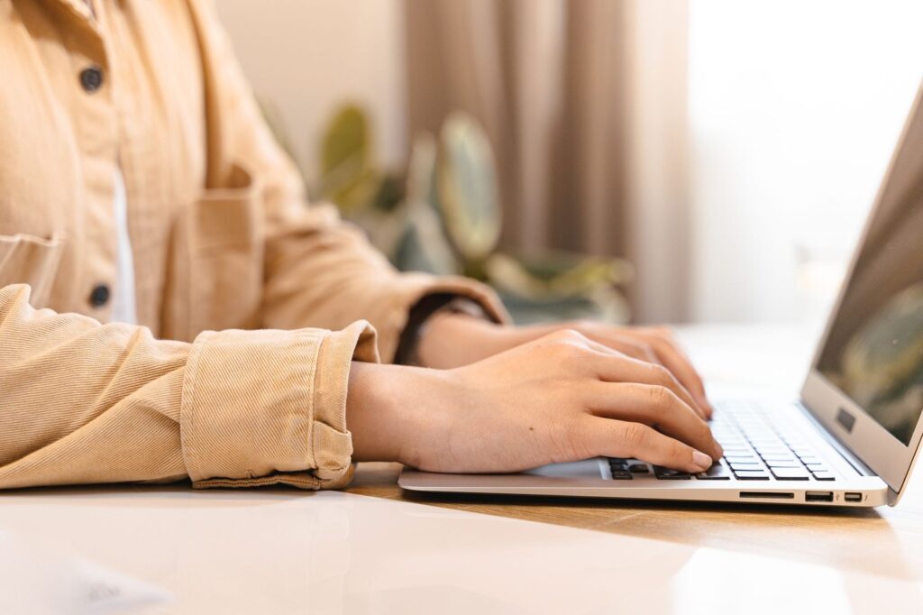 Hands typing on a laptop at a bright desk