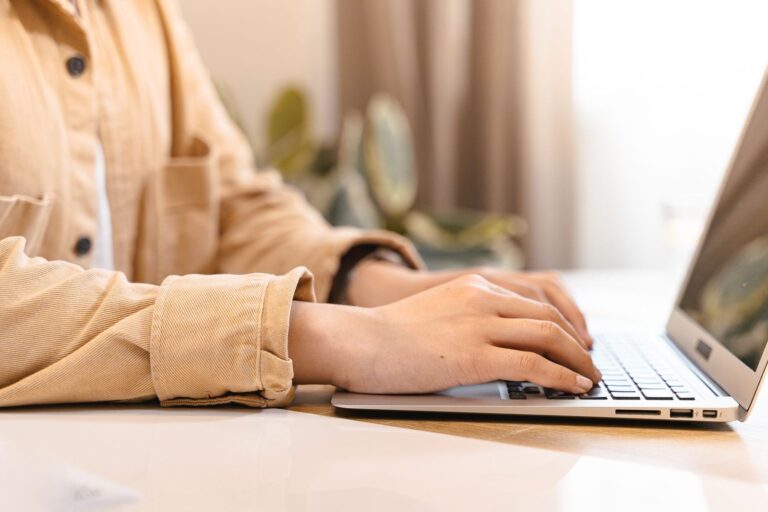Hands typing on a laptop at a bright desk